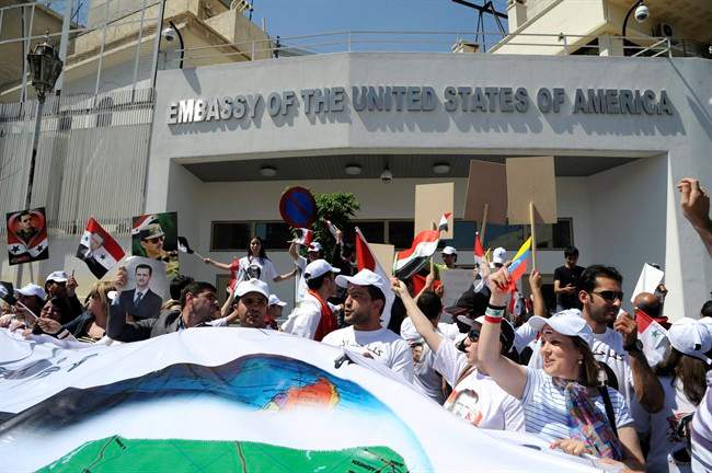 In this photo released by the Syrian official news agency SANA, Syrian pro-government supporters carry pictures of Syrian President Bashar Assad during a sit-in in front of the U.S. Embassy in Damascus, Syria, Wednesday, May 11, 2011. SANA said hundreds of Syrians held a demonstration Wednesday in front of the U.S. Embassy in Damascus to protest "U.S. intervention in the country's internal affairs." (AP Photo/SANA) EDITORIAL USE ONLY.