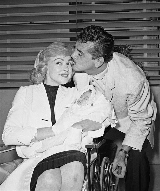 In this June 28, 1959 file photo, with cigar in hand, comedian Ernie Kovacs kisses his wife Edie Adams as she holds their daughter Mia at Cedars of Lebanon Hospital in Los Angeles, Calif. A new six-disk boxed set, "The Ernie Kovacs Collection," curates surviving treasures stretching from 1951 through his untimely death in 1962 will be released April 19, 2011. THE CANADIAN PRESS/AP Photo, file.