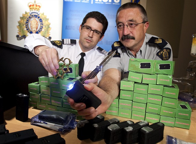 Calgary RCMP Sgt. Patrick Webb, right, and the Canadian Border Services Agency criminal investigation manager Richard Cuzzetto demonstrate a stun gun as they display a selection of recently seized stun guns, butterfly knives and brass knuckles at RCMP Southern Alberta District HQ in Calgary, Alta., Monday, May 9, 2011.The weapons were seized as part of a joint operation and as a result a Calgary man is facing numerous charges. THE CANADIAN PRESS/Jeff McIntosh.