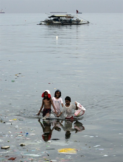 A group of children wade through the water near a sea wall in search of salvageable materials washed to the shore after a storm Tuesday, May 10, 2011 in Manila, Philippines. Tropical storm Aere blew away from northern Philippines, leaving at least 17 people dead but sparing vast agricultural regions where farmers welcome the rain. (AP Photo/Pat Roque).