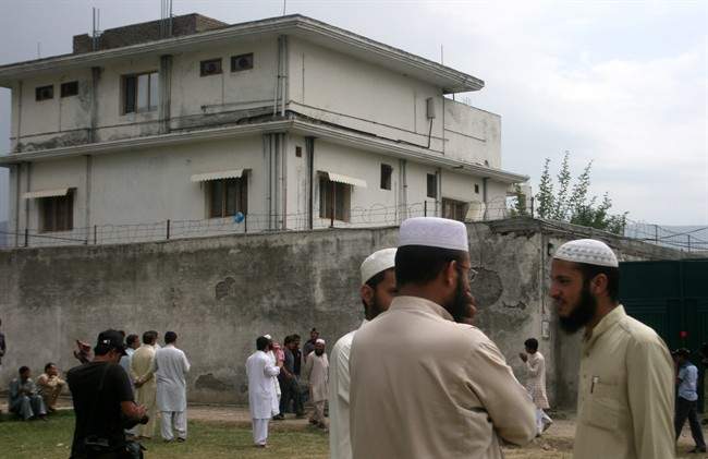 FILE - In this May 5, 2011 file photo, local residents and media are seen outside the house where al-Qaida leader Osama bin Laden was caught and killed in Abbottabad, Pakistan. The courier who led U.S. intelligence to bin Laden's hideout in Pakistan hailed from the Swat Valley, a one-time stronghold of militant Taliban fighters, Pakistani officials said on Wednesday, June 1, 2011. The officials identified the courier as Ibrahim Saeed Ahmed. He and his brother Abrar were shot dead in the daring U.S. Navy SEAL raid May 2 that also killed bin Laden and two other people. (AP Photo/Aqeel Ahmed, File).