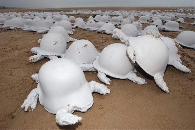 An installation of 1,000 casts of Russian, German and American combat helmets of WWII which also represent turtles, to denounce global violence, created by French artist Rachid Khimoune, is seen on Omaha Beach in Colleville sur Mer, western France, Sunday, June 5, 2011 at the eve of the D-Day Anniversary. (AP Photo/Vincent Michel).
