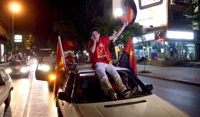 A supporter of the conservative VMRO-DPMNE, talks by phone atop of a car, while celebrating the party's victory on the parliamentary elections, in downtown Skopje, Macedonia, late Sunday, June 5, 2011. (AP Photo/Boris Grdanoski).