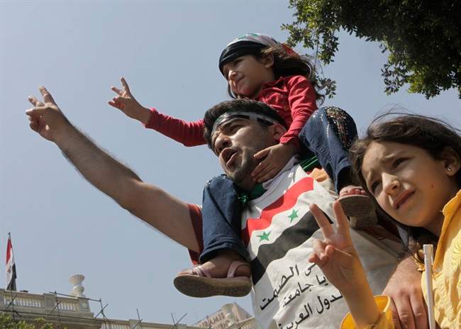A Syrian family shouts anti- Syrian President Bashar Asssad slogans as they wear Syrian independence flags during anti-Syrian regime protest outside the Arab League headquarters in Cairo, Egypt, Sunday, July 3, 2011, to support the Syrian demonstrators who protest in Syria against Bashar Assad's regime. Arabic on shirt reads "Arab League: till when your silence". (AP Photo/Amr Nabil).
