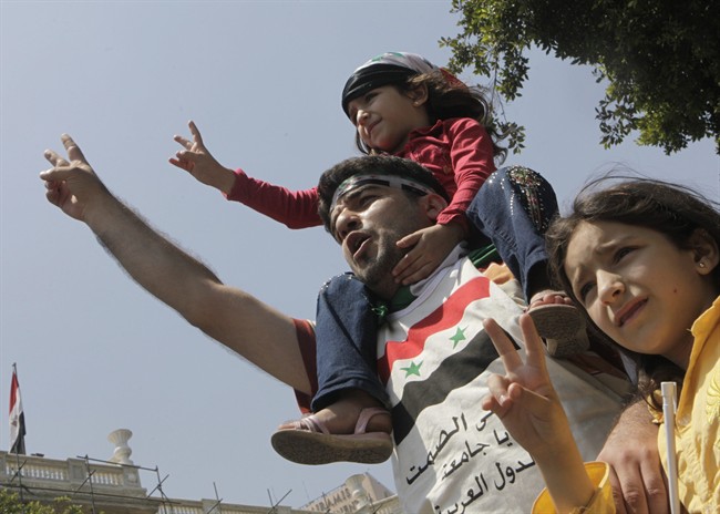 A Syrian family shouts anti- Syrian President Bashar Asssad slogans as they wear Syrian independence flags during anti-Syrian regime protest outside the Arab League headquarters in Cairo, Egypt, Sunday, July 3, 2011, to support the Syrian demonstrators who protest in Syria against Bashar Assad's regime. Arabic on shirt reads "Arab League: till when your silence". (AP Photo/Amr Nabil).