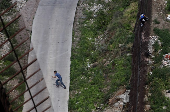 FILE - In this July 28, 2010 photo, two men illegally cross the border fence separating Nogales, Ariz., and Nogales, Sonora, Mexico, Arizona launched a website Wednesday, July 20, 2011, to accept donations to pay for fencing along the Mexico border, and a supporter says the $3.8 million people donated to defend the state's 2010 immigration enforcement law could be just a taste of what to expect. (AP Photo/Jae C. Hong, File).