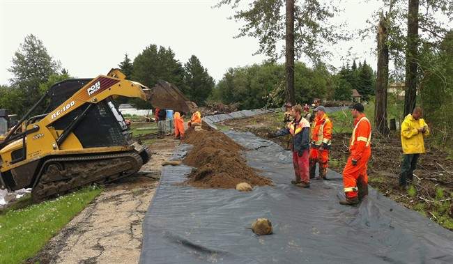 In this photo released by the RCMP, workers build a temporary dike to contain water near Slake Lake, Alta. on Saturday July 11, 2011. There's some good news for the residents of Slave Lake, Alta., who endured a wildfire that destroyed 400 homes and businesses earlier this spring only to face flooding this weekend. According to the Alberta government, the water level on the Sawridge Creek is dropping. THE CANADIAN PRESS/HO, RCMP.