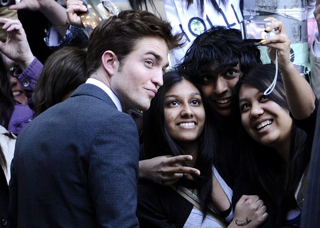 Actor Robert Pattinson takes pictures with fans at the premiere of "Water For Elephants" at the Ziegfeld Theater on Sunday, April 17, 2011, in New York. For many of Pattinson's most ardent Canadian fans, the summer of 2011 is better known as hunting season. Groupies eager for any tidbit of information about the British heart-throb's Toronto whereabouts have been in a frenzy trying to suss out what they can about his ongoing shoot on the David Cronenberg thriller “Cosmopolis.” THE CANADIAN PRESS/AP-Peter Kramer.