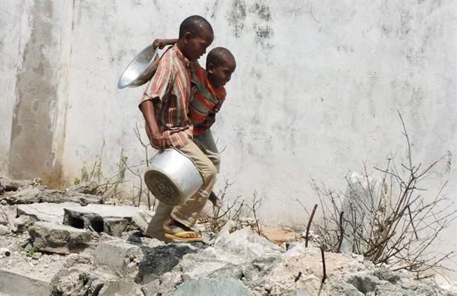 Two Somali children from southern Somalia, carrying a bowl and a pot, walk to a food distribution center in a camp for internally displaced people in Mogadishu, Somalia, Thursday, July 28 2011.