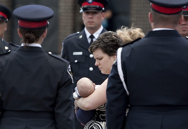 Melissa Styles, centre, the wife of slain York Regional Police Officer Constable Garrett Styles, holds their 10-week-old baby Nolan while walking past a line of police officers before her husband's remembrance service at the Ray Twinney Complex in Newmarket, Ontario Tuesday July 5, 2011. THE CANADIAN PRESS/Darren Calabrese.