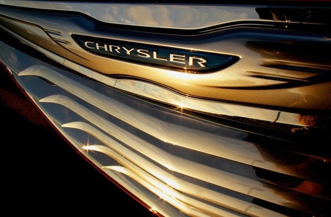 In this photo taken July 24, 2011, a setting sun is reflected in the front grill of a new Chrysler for sale at the Chrysler dealership in Springfield, Ill. 
