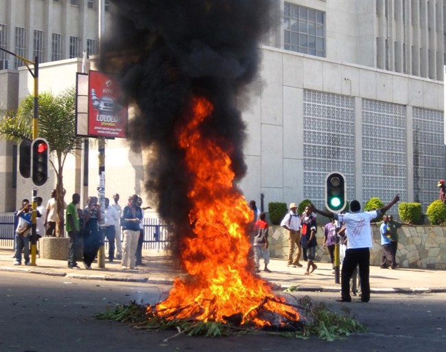 A protester burns vegetation in a street in Lilongwe, Malawi, Wednesday, July 20, 2011. Protesters went on the rampage after a court injunction stopped them protesting the economic and democratic crisis in the country. A coalition of more than 80 rights groups had organised nationwide protest marches for Wednesday. They wanted to protest what they say are moves by the Malawi's President Bingu wa Mutharika to roll back hard-fought democratic gains made since the first democratic polls in 1994 removed dictator Kamuzu Banda from power. (AP Photo/Diane Boles).