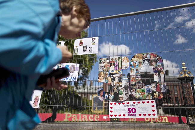 A woman looks at a montage of images of Princess Diana in the shape of a number fifty on fencing outside Kensington Palace in London, which was the residence of the princess, Friday, July 1, 2011. 