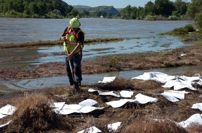 An ExxonMobil contractor cleans up oil along the banks of the Yellowstone River in Billings, Mont., Sunday, July 3, 2011.
