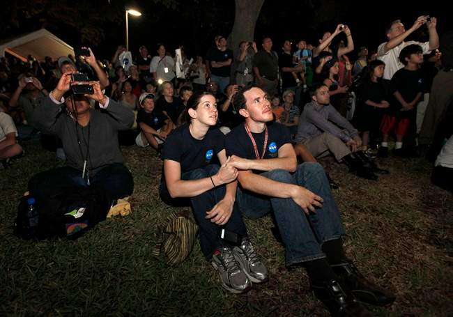 Johnson Space Center employees Jeremy Rea, right, and Shelley Stortz, left, hold hands as they watch space shuttle Atlantis land Thursday, July 21, 2011, in Houston. The landing of Atlantis brings the space shuttle program to an end. (AP Photo/David J. Phillip).