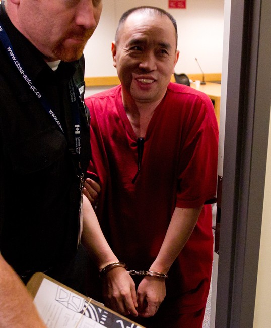 Lai Changxing is escorted by a security guard from an Immigration and Refugee Board detention hearing in Vancouver, B.C., on Monday July 11, 2011. THE CANADIAN PRESS/Darryl Dyck.