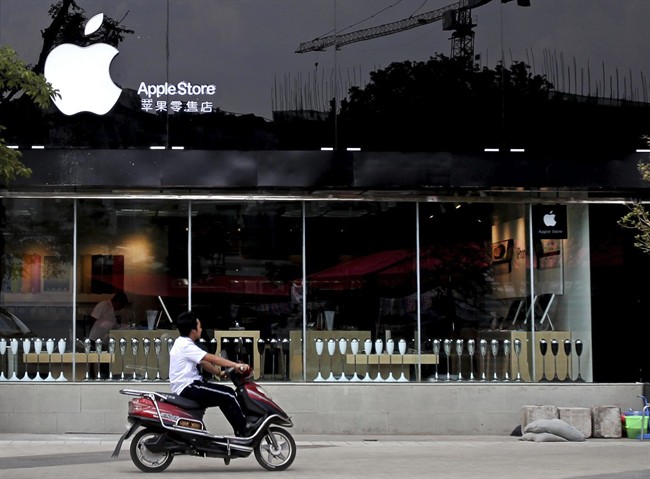 In this photo taken Thursday, July 21, 2011, a motorcyclist passes by a shop masquerading as a bona fide Apple store in downtown Kunming in southwest China's Yunnan province. China, long known for producing counterfeit consumer gadgets, software and brand name clothing, has reached a new piracy milestone, fake Apple stores. (AP Photo) CHINA OUT.