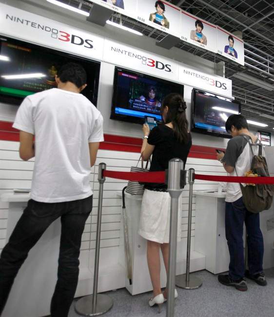 Shoppers try out Nintendo 3DS at an electronics retail store, in Tokyo, Japan, Thursday, July 28, 2011. Nintendo Co. says it stayed deep in the red in the latest quarter, prompting the Japanese video game giant to cut its full-year forecasts and slash prices on its new 3DS handheld device. (AP Photo/Shizuo Kambayashi).