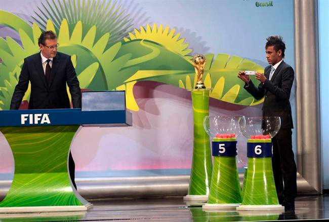 Brazil's soccer player Neymar, right, holds up the name of an African country, as FIFA general secretary and master of ceremonies Jerome Valcke looks on at the Preliminary Draw of the 2014 FIFA World Cup Brazil in Rio de Janeiro, Brazil, Saturday July 30, 2011. The 2014 World Cup takes shape Saturday as the qualifying draw lays out each nation's path to securing a spot in the tournament in three years' time. The draw will determine the layout of the qualifying groups for Africa; North, Central America and the Caribbean; Asia; Europe; and Oceania. (AP Photo/Silvia Izquierdo).