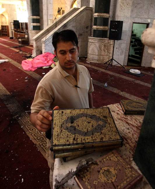 A man inspects copies of the Quran, Muslims holy book, covered with blood, at Um al-Qura mosque in Baghdad, Iraq, Monday, Aug. 29, 2011. A suicide bomber blew himself up inside Baghdad's largest Sunni mosque Sunday night, killing dozens during prayers, a shocking strike on a place of worship similar to the one that brought Iraq to the brink of civil war five years ago. (AP Photo / Khalid Mohammed).
