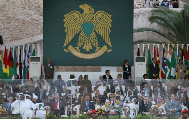 FILE - In this Sept. 1, 2009 file photo, Libyan leader Moammar Gadhafi, center right, and Venezuelan President Hugo Chavez, center left, sit behind bulletproof glass and observe a military parade in Green Square, Tripoli, Libya. Even after rebels stormed into the capital and overwhelmed his residence, Libya's Moammar Gadhafi has plenty of places to hide. The man who ruled Libya for 42 years is known to have deep bunkers under his Bab al-Aziziya compound in Tripoli, which rebel fighters seized Tuesday, Aug. 23, 2011. Some former officials say the compound is connected by long tunnels to far-flung parts of Tripoli in a hidden network that would provide a quick escape route. (AP Photo/Ben Curtis, File).