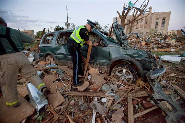Police examine a crushed vehicule after a powerful storm ripped through Goderich, Ont. on Sunday, August 21, 2011. THE CANADIAN PRESS/ Geoff Robins.