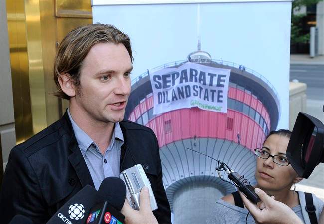 Greenpeace spokesman Mike Hudema makes a statement outside the Courts Centre in downtown Calgary on Friday, Aug. 5, 2011 after seven Greenpeace activists were fined for mischief at a popular Calgary tourist attraction last summer. Beside him is a large photo from the event. THE CANADIAN PRESS/Larry MacDougal.
