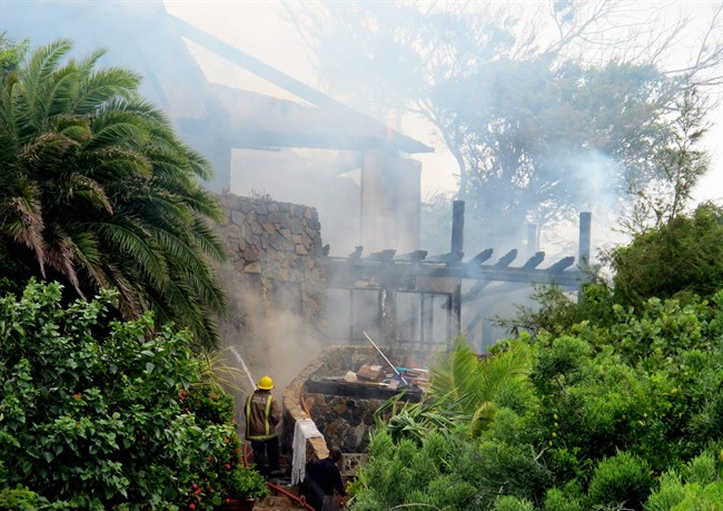 In this image issued Monday Aug. 22, 2011 by Virgin Limited Edition shows a firefighter spraying British entrepreneur's Sir Richard Branson's luxury home, on Necker Island, in the Caribbean, which was damaged by a fire which ripped through the luxury home. Guests including Academy Award-winning actress Kate Winslet escaped uninjured when fire destroyed Richard Branson's Caribbean home during a tropical storm Monday, said the British businessman. The Virgin Group boss said about 20 people, including Winslet and her children, were staying in the eight-bedroom Great House on Necker, his private isle in the British Virgin Islands. (AP Photo/Virgin Limited Edition/PA) UNITED KINGDOM OUT NO SALES NO ARCHIVE EDITORIAL USE ONLY.