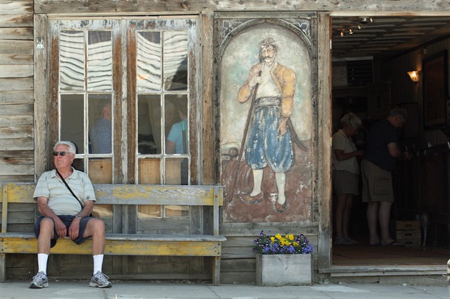 In this July 28, 2011 photo, a visitor sits outside the Gypsy Museum which houses an antique Gypsy fortune teller machine, in Virginia City, Mont., and has received multimillion dollar offers from curators including magician David Copperfield. Collectors say the 100-year-old machine that speaks your fortune may be the last of its kind. (AP Photo/Michael Albans).