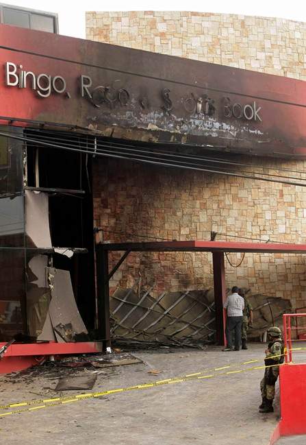 A soldier stands guard outside the Casino Royale after a deadly assault in Monterrey, Mexico, Friday, Aug. 26, 2011. Mexican officials say a group of at least eight assailants poured gasoline inside the casino before setting it on fire on Thursday, trapping dozens of people inside and killing at least 52 people. (AP Photo/Arnulfo Franco).