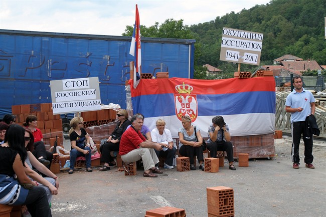 Kosovo Serbs sit in front of a barricade in northern Kosovo near the village of Rudare on Saturday, July 30, 2011. European Union on Friday urged Serbia and Kosovo to reduce tensions after a series of incidents on their border. Serbs blocked roads on Friday and have attacked border posts, firing at NATO peacekeepers in an attempt to keep control over Kosovo's north, which despite a NATO and EU presence remains under Serbia's realm. (AP Photo).