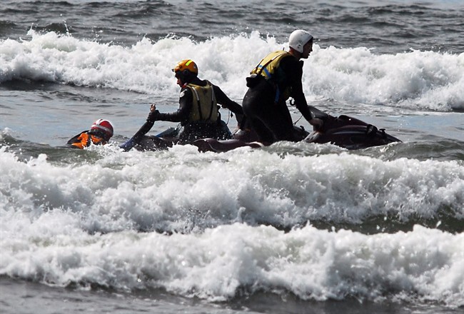 Surf rescue swimmers Eddie Mendez and Will Green pull Dale Ostrander aboard their jet ski after finding him in the surf off the Cranberry Rd. beach approach near Long Beach, Wash+., Friday, Aug. 5, 2011. The team searched for the boy for nearly 15 minutes before locating him. (AP Photo/Damian Mulinix/Chinook Observer).