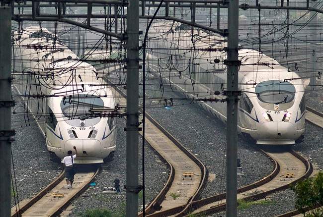 A train technician waves as he approaches CRH high-peed trains stopped on tracks at Beijing South Station in Beijin Friday, Aug. 12, 2011. A Chinese bullet train manufacturer recalled 54 trains Friday in a new embarrassment for a problem-plagued prestige project following a July crash that killed 40 people. (AP Photo/Alexander F. Yuan).