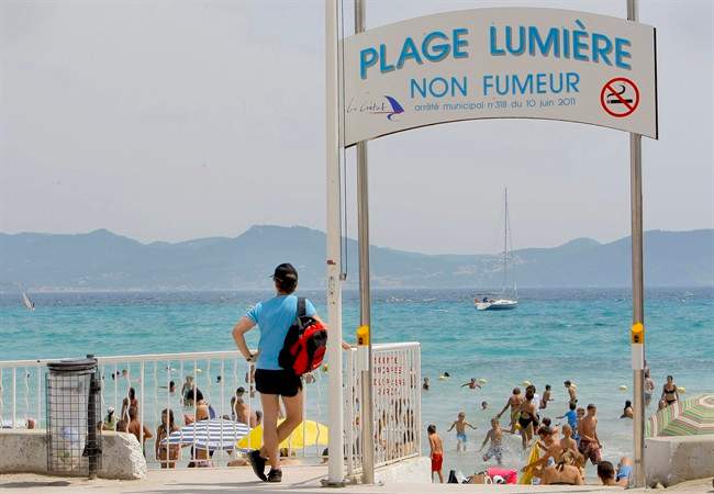 In this Aug. 2, 2011 photo, French tourists are ssen at La Ciotat beach near Marseille, southern France. A small town in Provence has found an unusual way to attract more vacationing families to its sun-drenched white sand beach: ban smoking from one stretch of its Mediterranean sea front, eliminating the cigarette butts dropped by careless smokers that find their way into children's' sand castles or worse, mouths. Banner reads: "Light Beach, No Smoking." (AP Photo/Jacques Brinon).