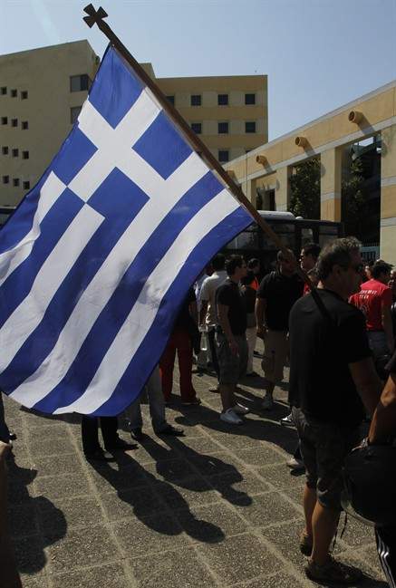 A protesting taxi driver carries a Greek national flag in front of the transport ministry during a protest in Athens on Wednesday, Sept 28, 2011. About 2000 striking taxi drivers gathered to protest against government plans to open up their licensed profession to more competition.(AP Photo/Kostas Tsironis).