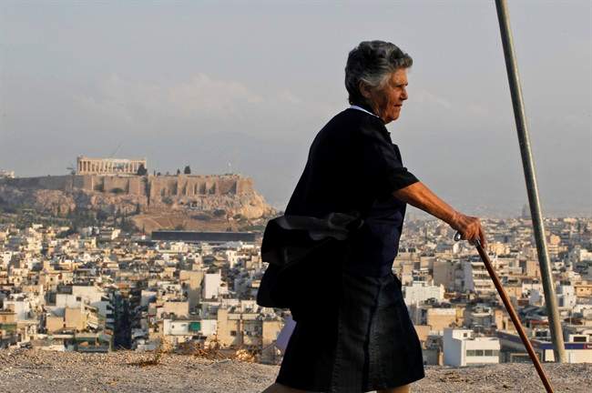 An elderly woman walks backdropped by the ancient Acropolis hill and the city of Athens, on Monday, Sept, 26, 2011. Athens commuters faced more misery as metro, tram and suburban rail workers were on a 24-hour strike, while buses and trolleys were to stop operating for several hours in the middle of the day. As the prospect of a disastrous debt default hung over Greece, the government faced more strikes and protests against its new austerity measures needed to appease the country's rescue creditors. (AP Photo/Petros Giannakouris).