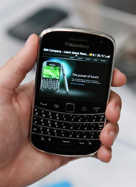 An investment bank with holdings in Research In Motion is urging fellow shareholders to push the BlackBerry maker to explore its strategic options, including potentially selling or splitting up the company. An employee holds a Blackberry Bold Touch smart phone at the Research in Motion annual meeting in Waterloo, Ontario, July 12, 2011. THE CANADIAN PRESS/Dave Chidley.
