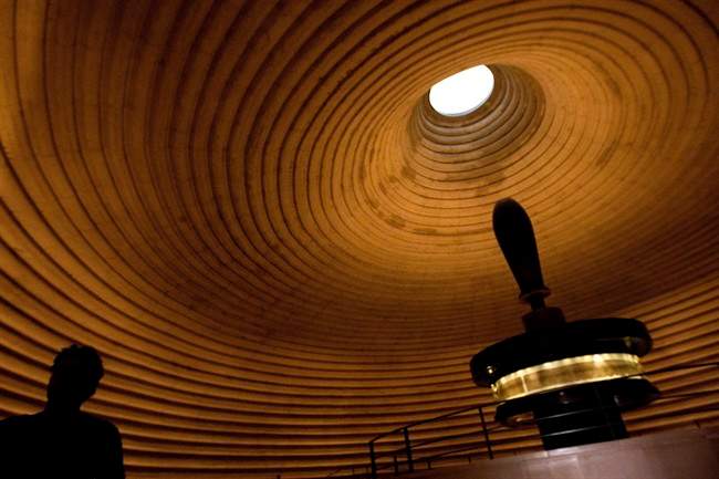 A tourist is silhouetted standing near a replica of the Dead Sea Scrolls on display, inside the Shrine of the Book building at the Israel Museum in Jerusalem, Monday, Sept. 26, 2011. Two thousand years after they were written and decades after they were found in desert caves, some of the world-famous Dead Sea Scrolls are available online. Israel's national museum and the international web giant Google are behind the project, which saw five scrolls go online Monday. (AP Photo/Sebastian Scheiner).