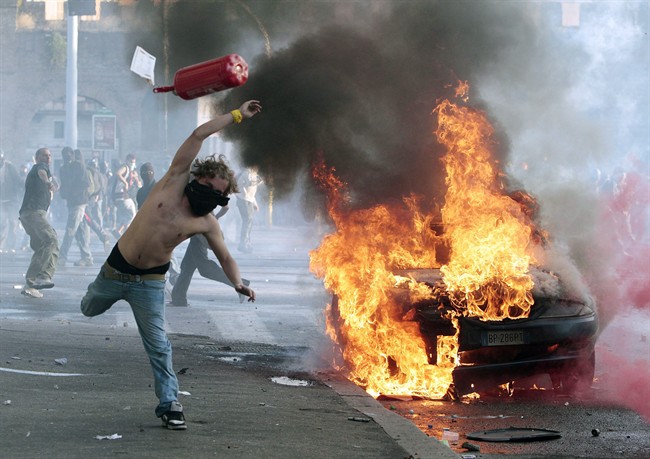 A protestor hurls a canister towards police next to a burning car during clashes in Rome, Saturday, Oct. 15, 2011. Protesters in Rome smashed shop windows and torched cars as violence broke out during a demonstration in the Italian capital, part of worldwide protests against corporate greed and austerity measures, entitled Occupy Wall Street. (AP Photo/Gregorio Borgia).
