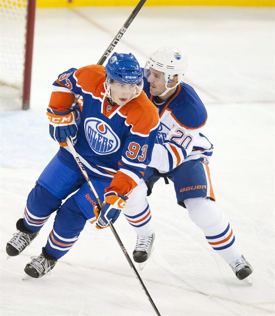 Edmonton Oilers' Ryan Nugent-Hopkins, left, dodges Oilers' Eric Belanger, during NHL hockey pre-season split-squad Joey Moss Cup action in Edmonton on Sunday, September 18, 2011. Those who thought Nugent-Hopkins would back riding a bus when his first training camp with the Edmonton Oilers concluded had it half-right. THE CANADIAN PRESS/John Ulan.