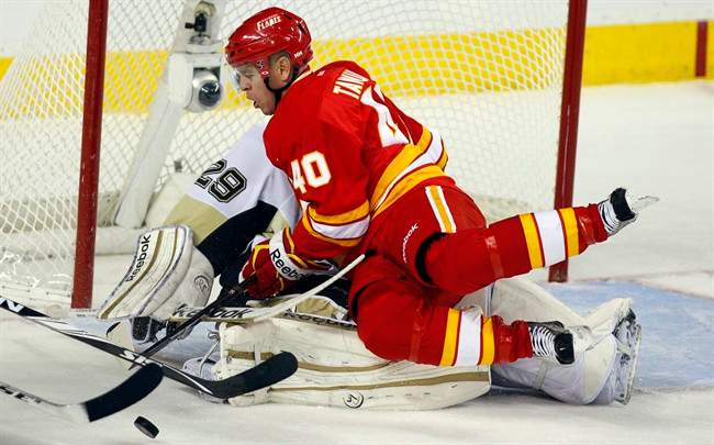 Pittsburgh Penguins goalie Marc-Andre Fleury, left, collapses under the wieght of Calgary Flames' Alex Tanguay during second period NHL hockey action in Calgary, Alta., Saturday, Oct. 8, 2011.THE CANADIAN PRESS/Jeff McIntosh.