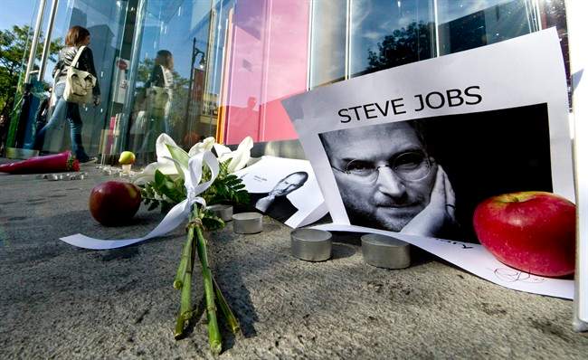 A woman walks past a memorial for Apple co-founder and former CEO Steve Jobs who died Wednesday as she enters an Apple Store Thursday, October 6, 2011 in Montreal. THE CANADIAN PRESS/Paul Chiasson.
