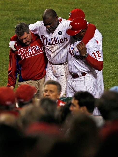 Philadelphia Phillies first baseman Ryan Howard, center, is helped off the field after being injured while making the last out during the ninth inning of baseball's Game 5 of the National League division series with the St. Louis Cardinals Friday, Oct. 7, 2011 in Philadelphia. Cardinals won 1-0. (AP Photo/Mel Evans).