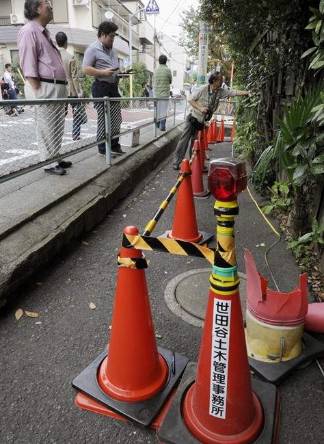 A no-entry zone is set up on a sidewalk Thursday, Oct. 13, 2011 in Tokyo's Setagaya district where officials found a radiation hotspot Wednesday. Officials investigating the hotspot have tracked down its source Thursday to old bottles stored in an empty house's basement. The words on a traffic corn reads "Setagaya Civil Engineering Office." (AP Photo/Kyodo News) JAPAN OUT, MANDATORY CREDIT, NO LICENSING IN CHINA, FRANCE, HONG KONG, JAPAN AND SOUTH KOREA.