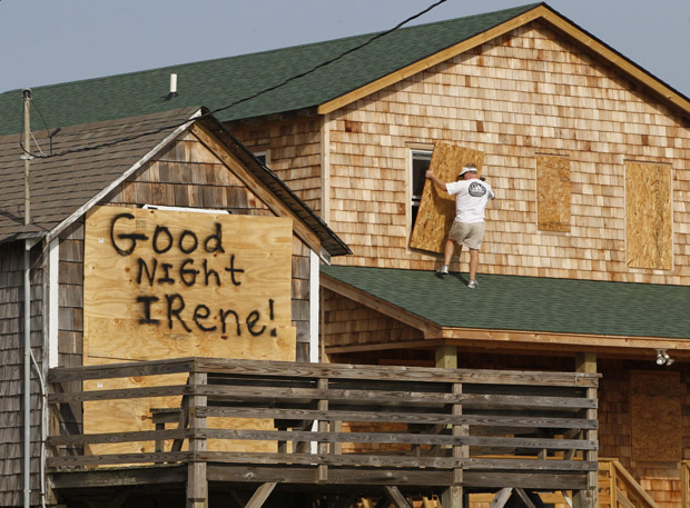 A message is left for Hurricane Irene on one house, left, as a resident boards up another in anticipation of the arrival of Hurricane Irene in Nags Head, N.C., Thursday, Aug. 25, 2011 on North Carolina's Outer Banks.
