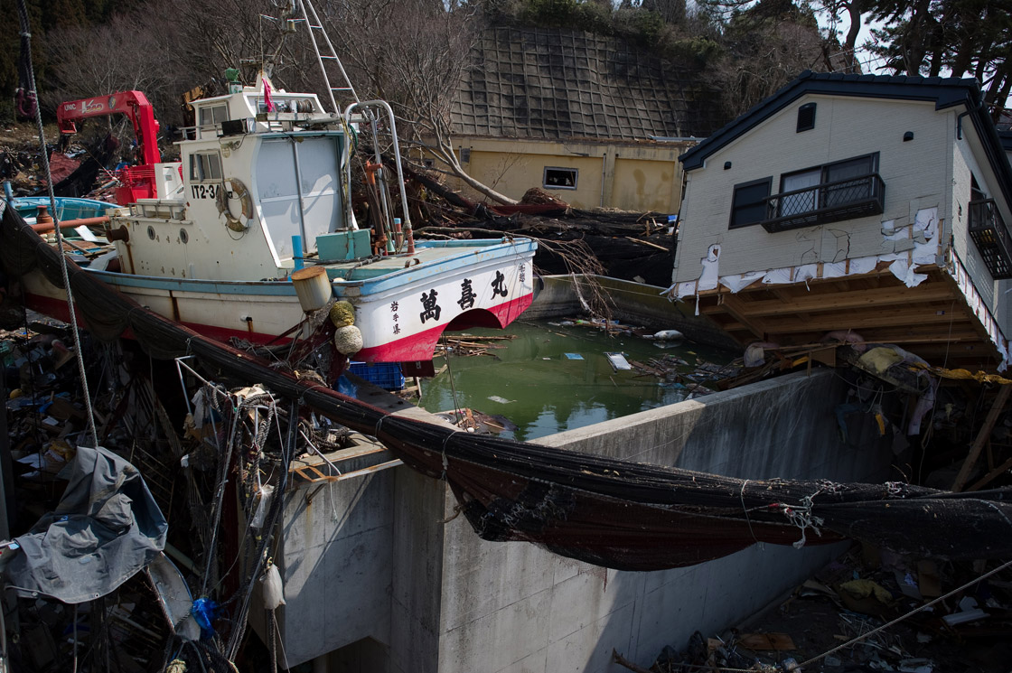 A washed up boat and destroyed house lie on the roof of a building in the tsunami-damaged town of Yamada, in Iwate prefecture, on March 25, 2011. Two weeks after a giant quake struck and sent a massive tsunami crashing into the Pacific coast, the death toll from Japan's worst post-war disaster topped 10,000 and there was scant hope for 17,500 others still missing. 