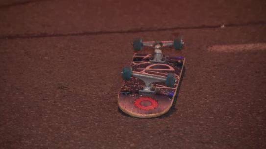 A skateboard lays upside down on the street following an incident.