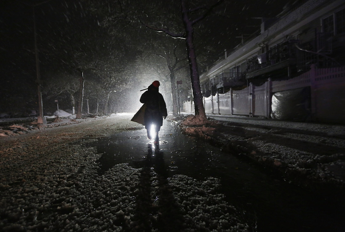 A repair worker is silhouetted by a police spotlight as he walks down a darkened street during a Nor’Easter snowstorm on November 7, 2012 in the Rockaway neighborhood of the Queens borough of New York City. The Rockaway Peninsula was especially hard hit by Superstorm Sandy and some are evacuating ahead of the coming storm. 