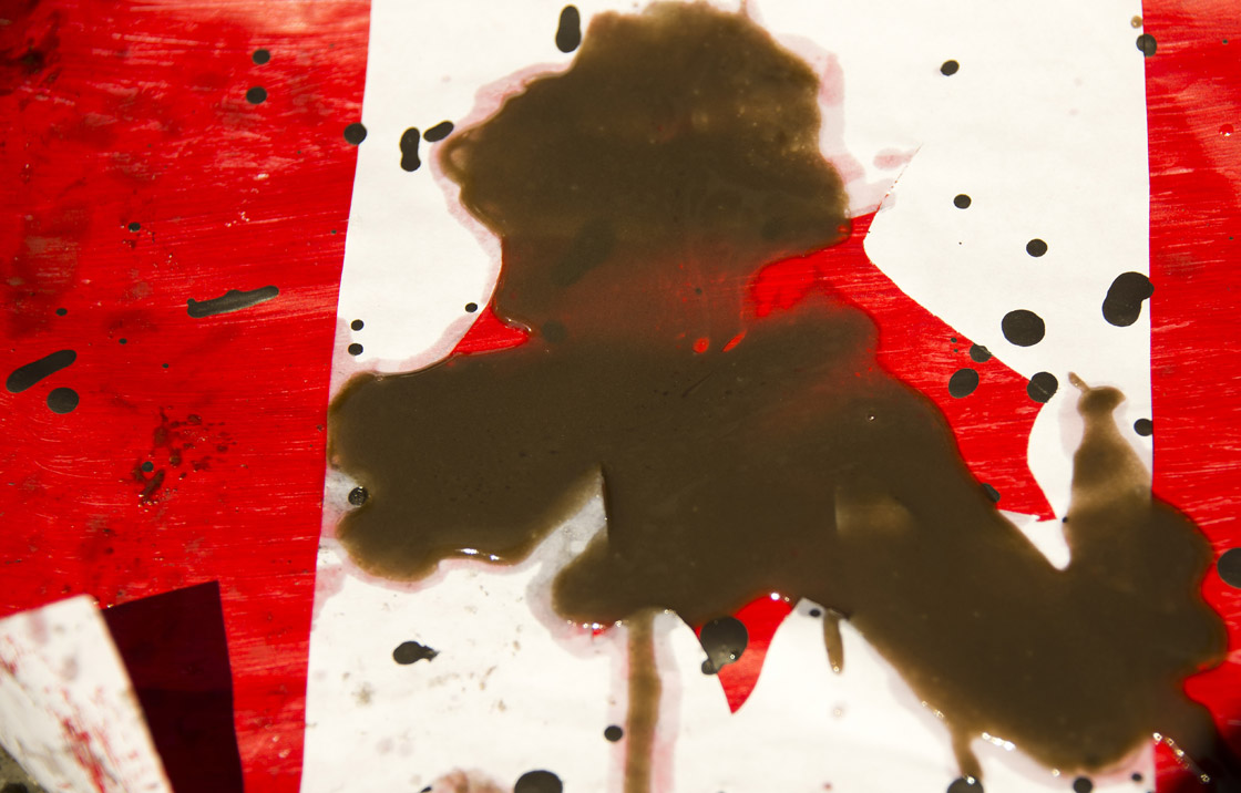 A placard with the Canadian flag rest on the ground covered in oil as demonstrators conduct a die-in covered in oil as they protest against the Keystone Pipline and the Alberta Tar Sands in Chicago, Illinois, May 17, 2012 ahead of the NATO 2012 Summit.