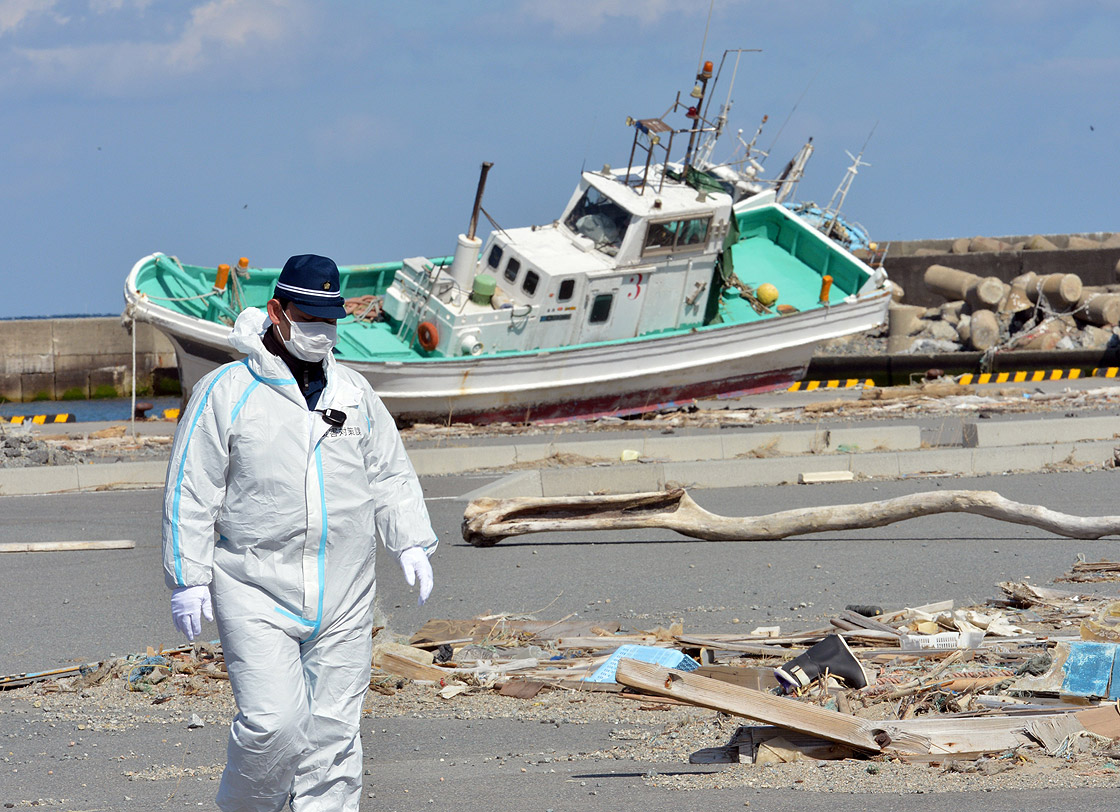 A police officer walks on a pier to search for missing people as a wrecked ship still rests grounded in Namie, near TEPCO's Fukushima Dai-ichi nuclear plant in Fukushima prefecture on March 11, 2013. 